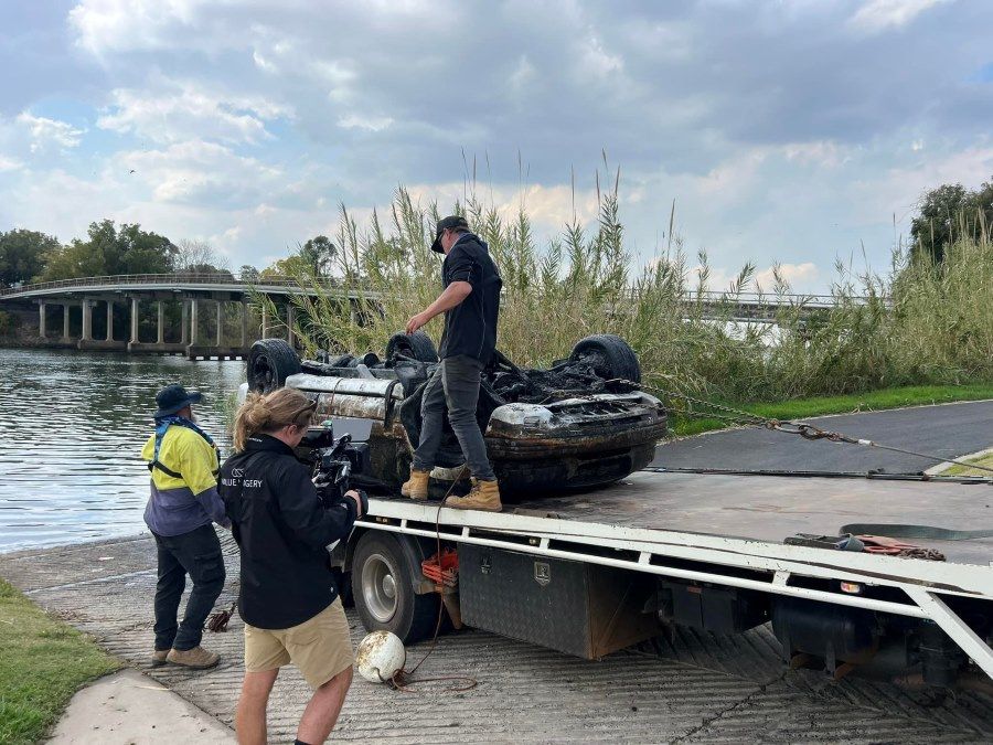 A Group of People Are Loading a Boat Onto a Tow Truck — TNT Towing - Coffs Clarence in Woolgoolga, NSW
