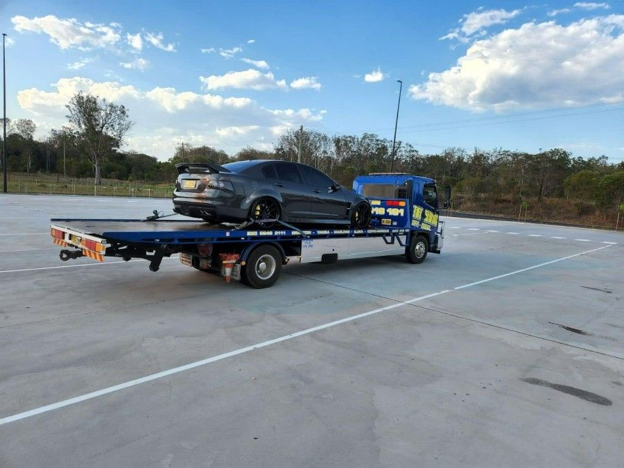 A Tow Truck is Towing a Car in a Parking Lot — TNT Towing - Coffs Clarence in Casino, NSW