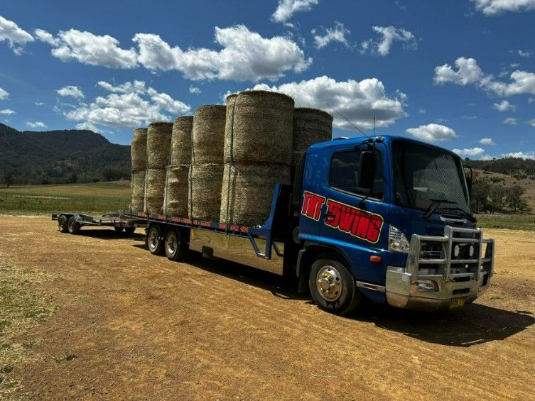 A Blue Truck is Carrying Bales of Hay on a Trailer — TNT Towing - Coffs Clarence in Northern Rivers, NSW