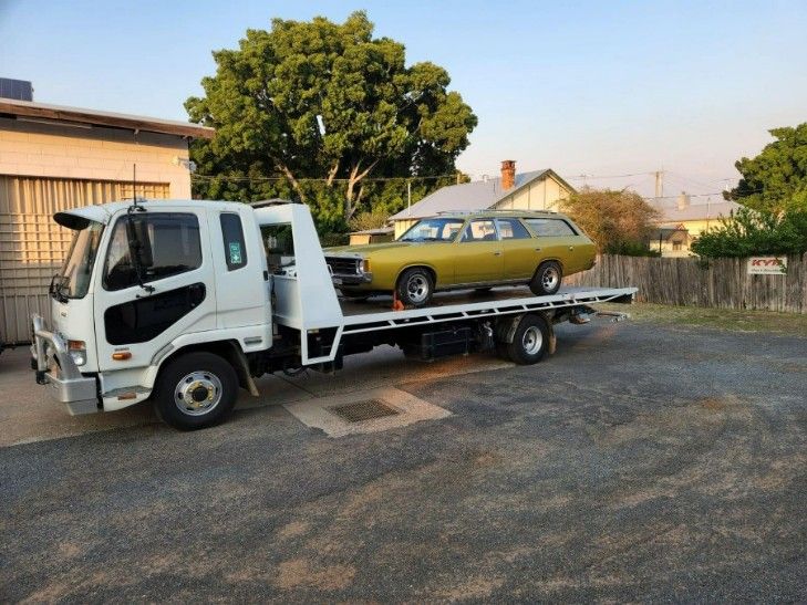 A Yellow Car is Being Towed by a Tow Truck — TNT Towing - Coffs Clarence in Yamba, NSW