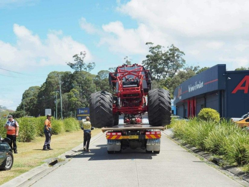 A Red Monster Truck is Being Towed Down a Street — TNT Towing - Coffs Clarence in South Grafton, NSW