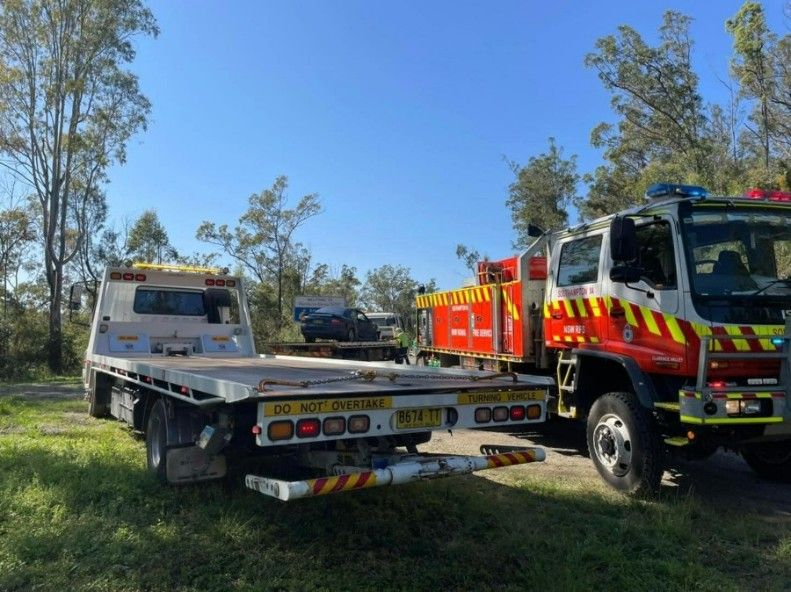 Two Tow Trucks Are Parked Next to Each Other in a Grassy Area — TNT Towing - Coffs Clarence in Northern Rivers, NSW