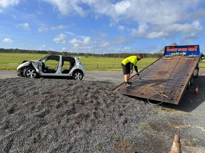 A Man is Loading a Car Onto a Tow Truck — TNT Towing - Coffs Clarence in Iluka, NSW