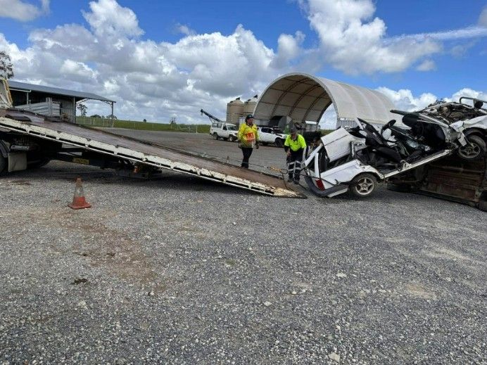 A Tow Truck is Carrying a Wrecked Car on the Back of It — TNT Towing - Coffs Clarence in Evans Head, NSW