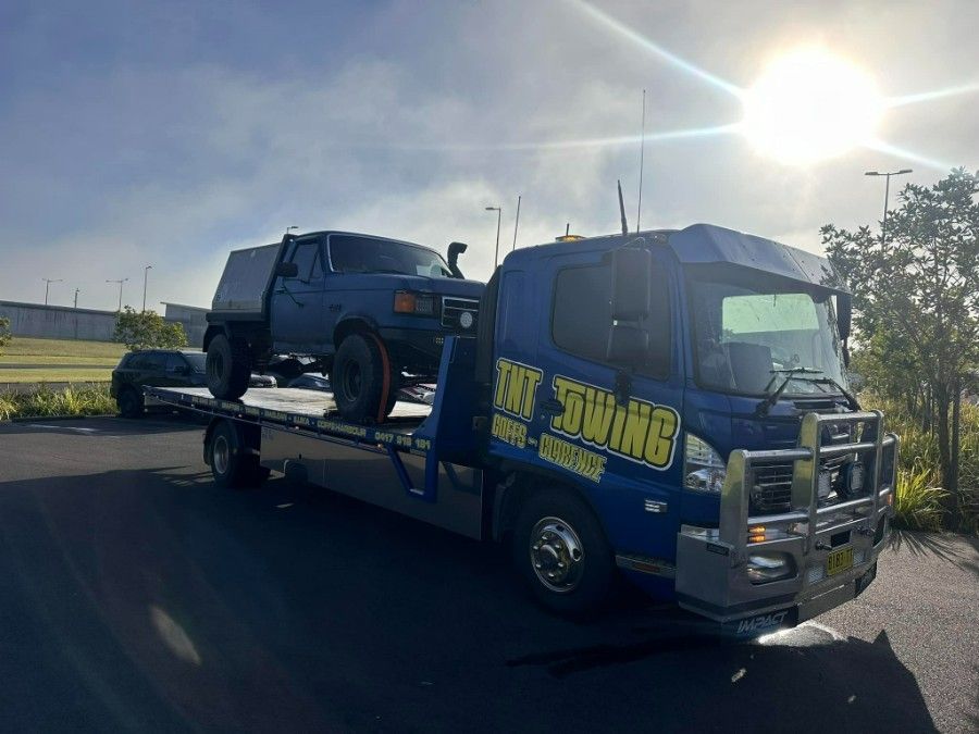 A Blue Tow Truck is Carrying a Truck on the Back of It — TNT Towing - Coffs Clarence in Ballina, NSW