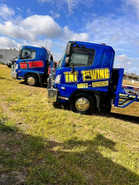 Two Blue TNT Trucks Are Parked Next to Each Other in a Grassy Field — TNT Towing - Coffs Clarence in Ballina, NSW