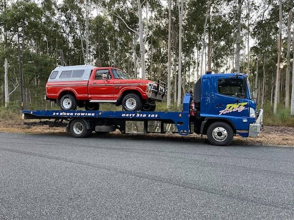A Red Truck is Being Towed by a Blue Tow Truck — TNT Towing - Coffs Clarence in South Grafton, NSW