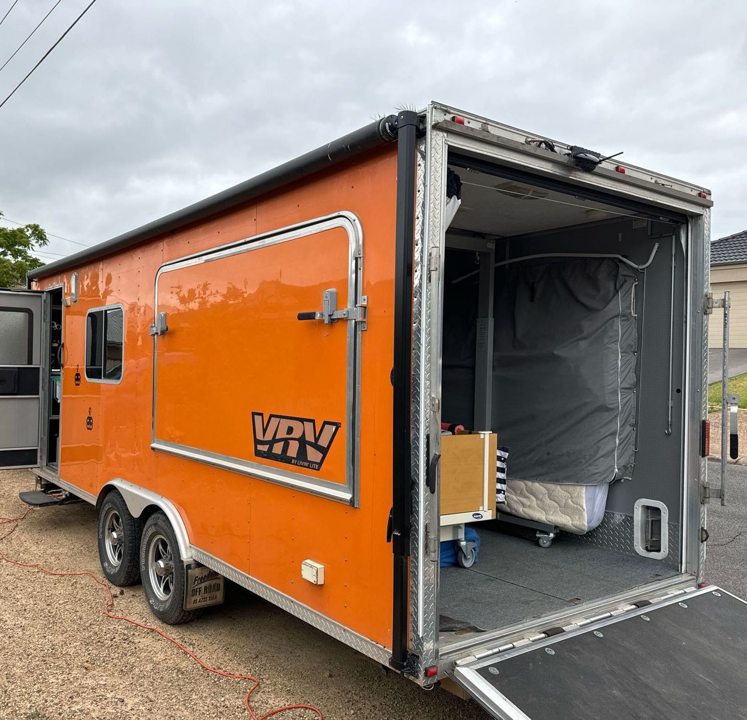 An orange trailer with the door open is parked on the side of the road.