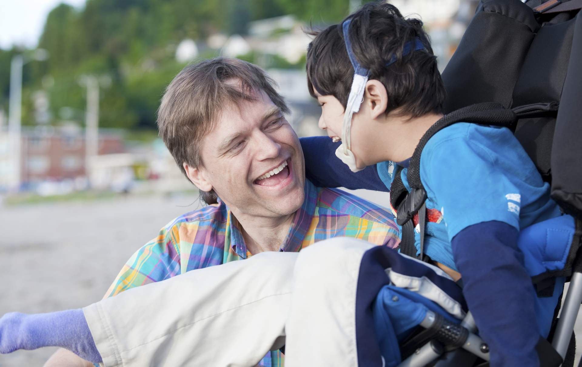 A man is sitting next to a boy in a wheelchair.