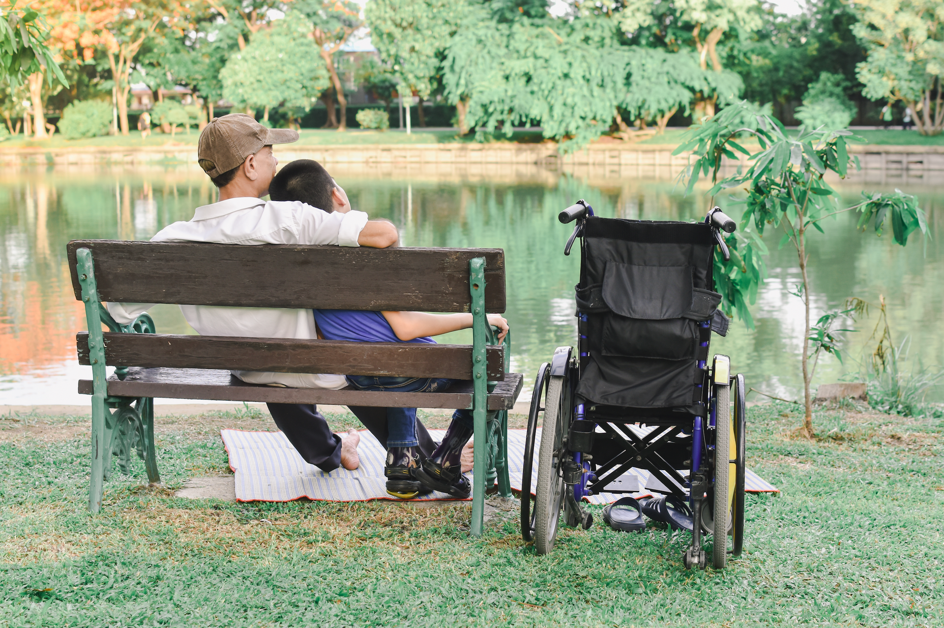 A man and a woman are sitting on a park bench next to a wheelchair.