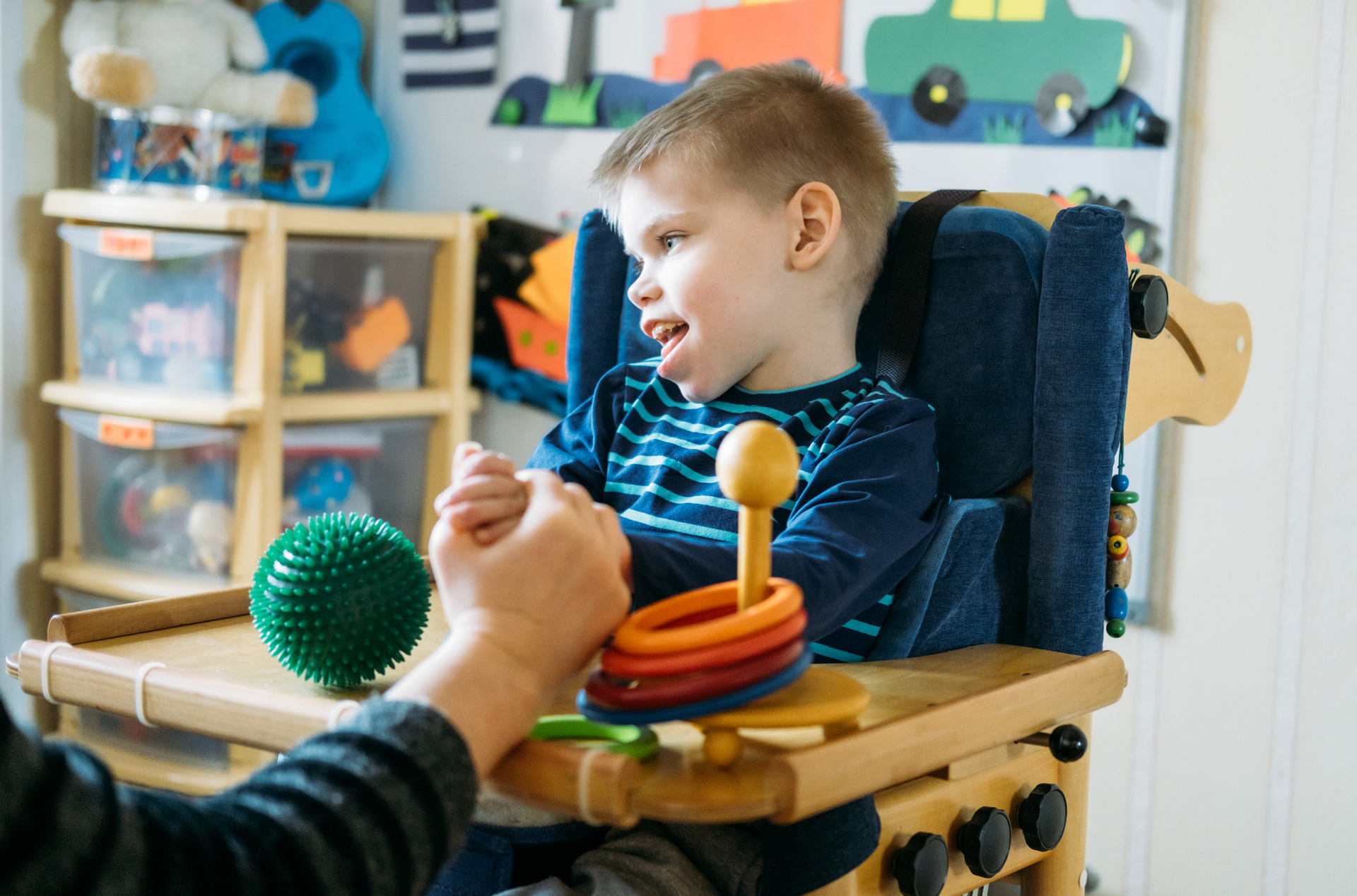 A young boy is sitting in a high chair playing with toys.
