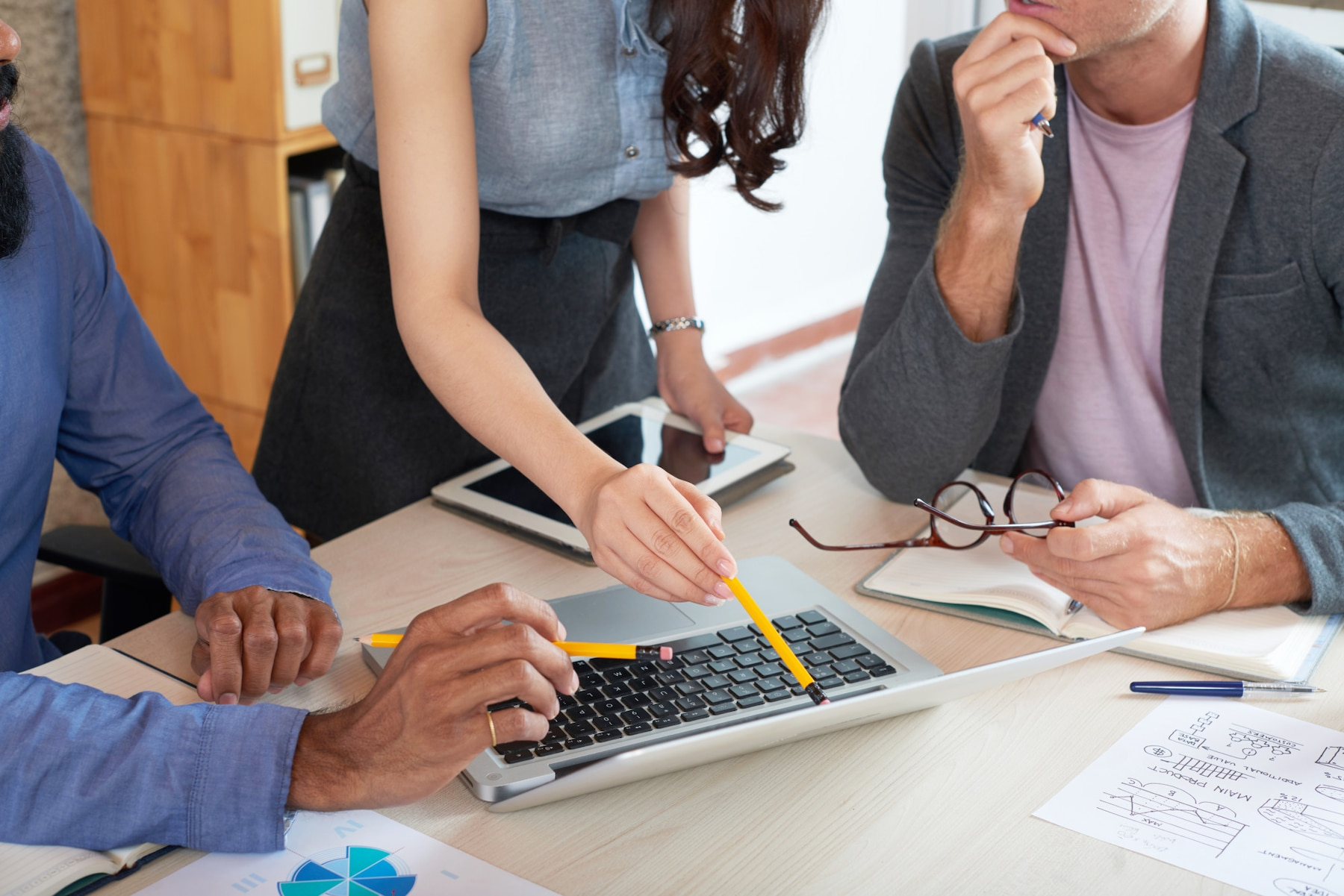 A group of people are sitting at a table looking at a laptop computer.