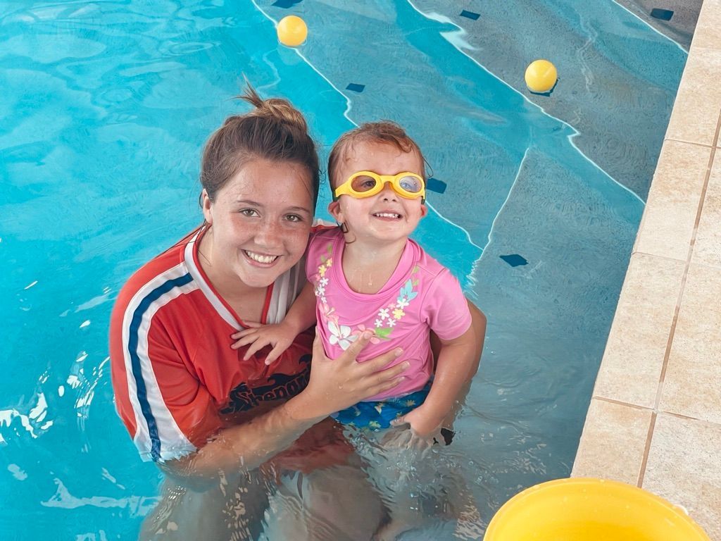 A woman is holding a little girl in a swimming pool.