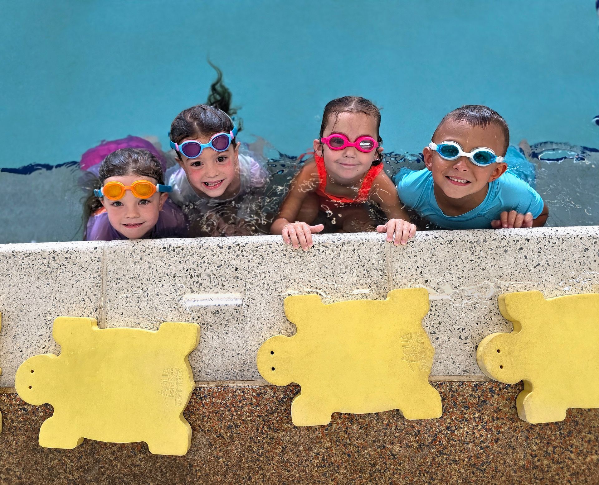 A group of children are sitting on the edge of a swimming pool