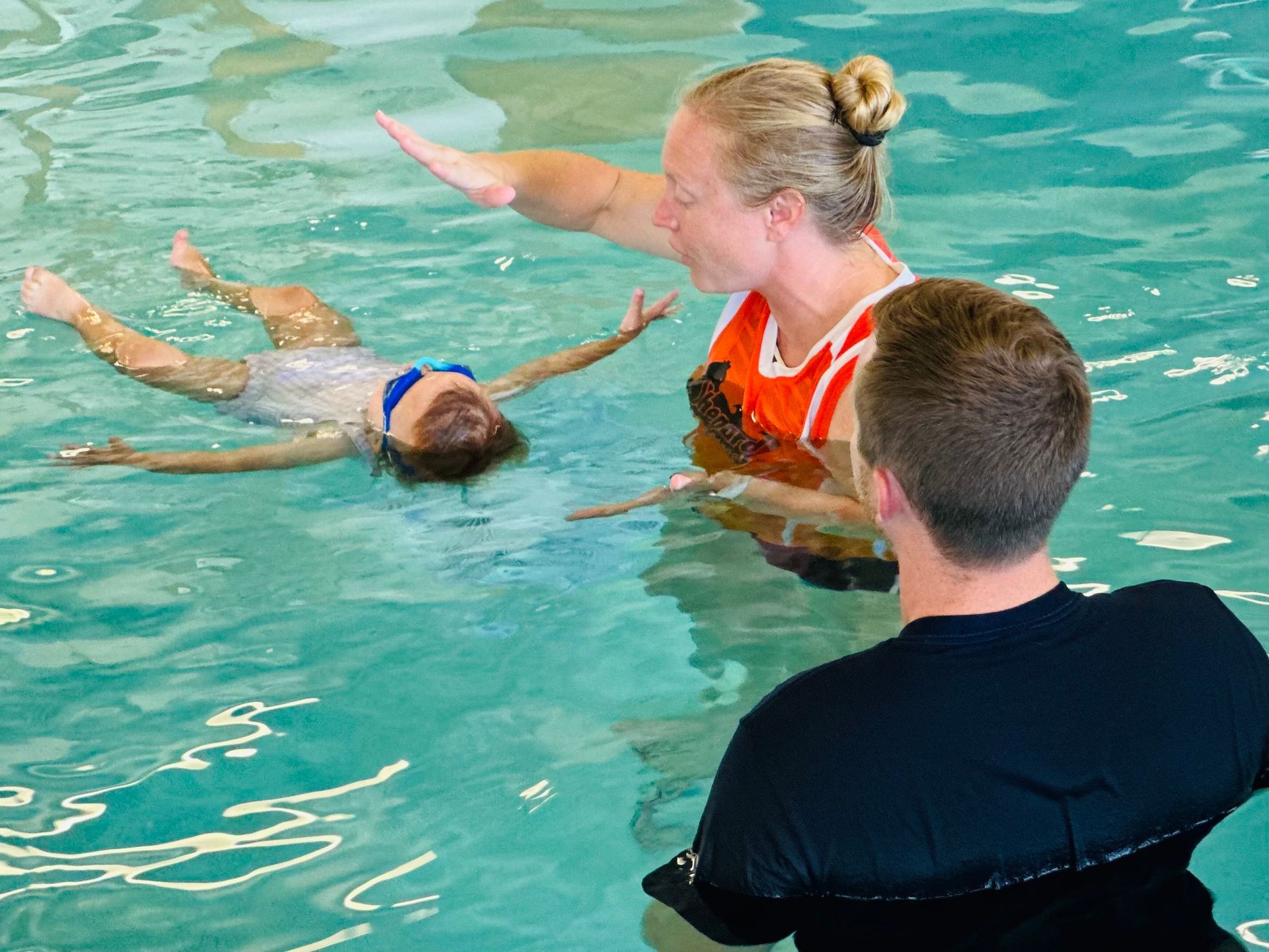 A woman is teaching a child how to swim in a swimming pool.