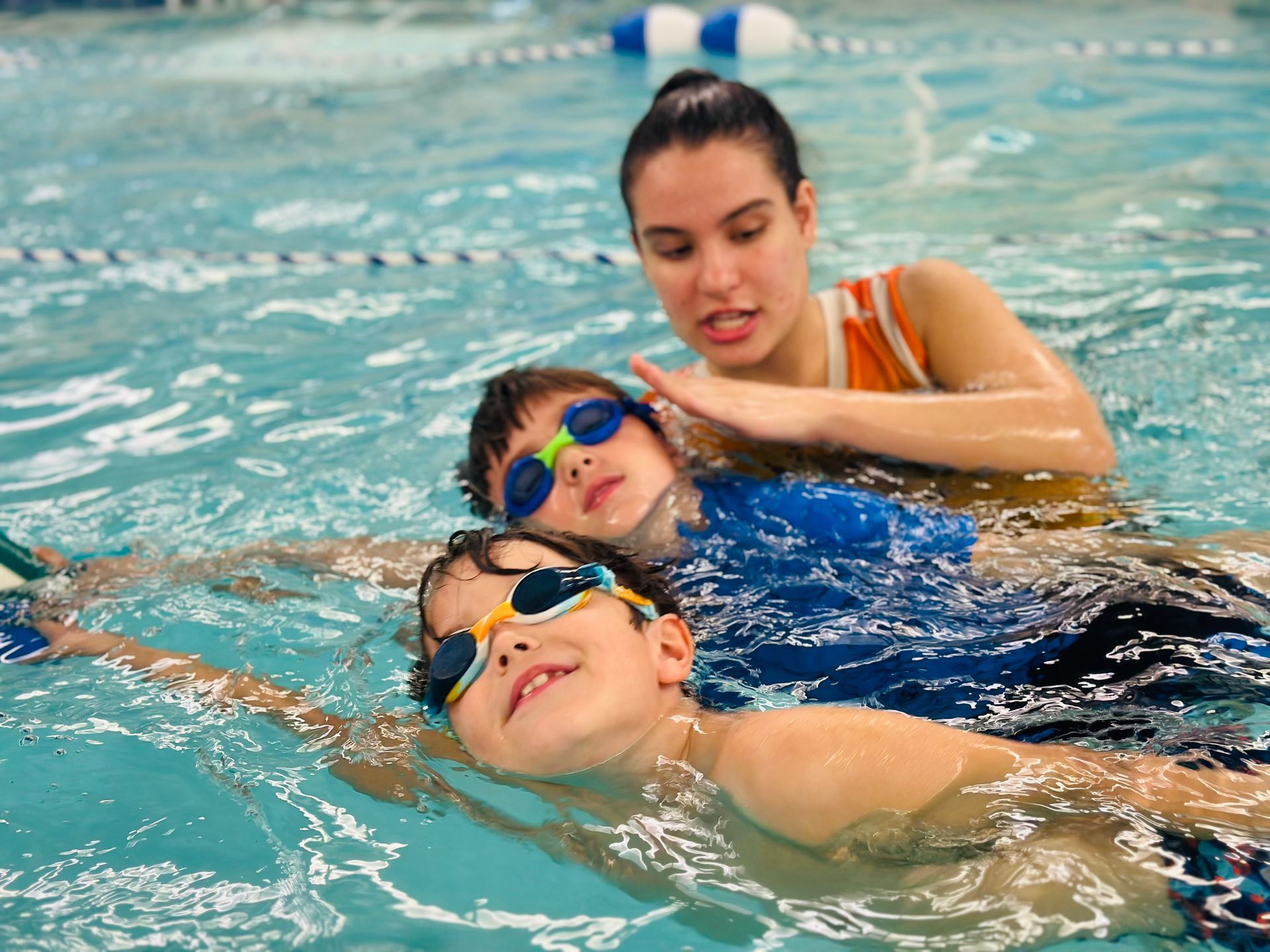 A woman is teaching a young boy how to swim in a swimming pool.