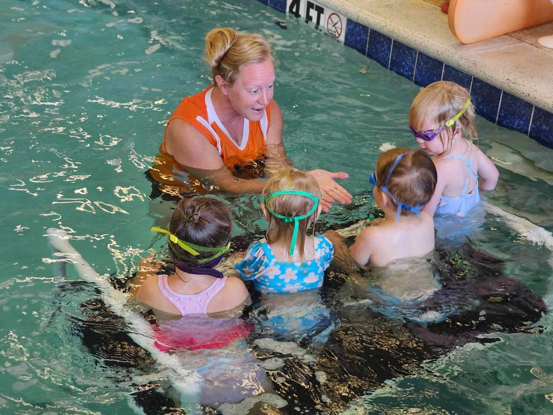 A woman is talking to a group of children in a swimming pool.