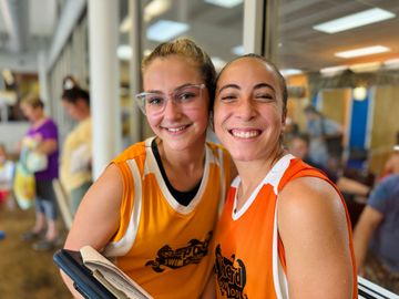 Two girls in basketball uniforms are posing for a picture.