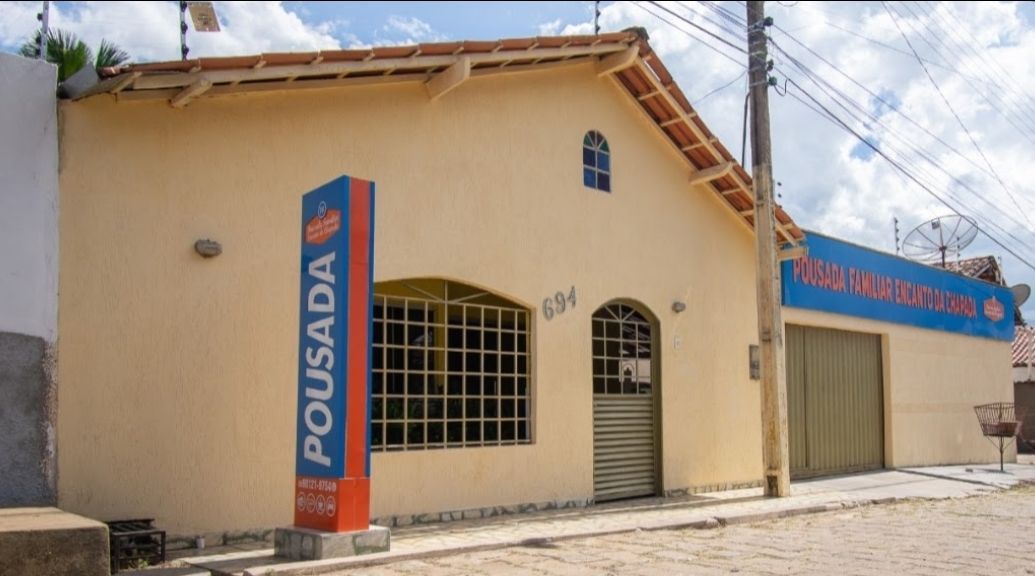 Prédio bege com uma placa azul "POSADA" na esquina e uma porta estilo garagem.
