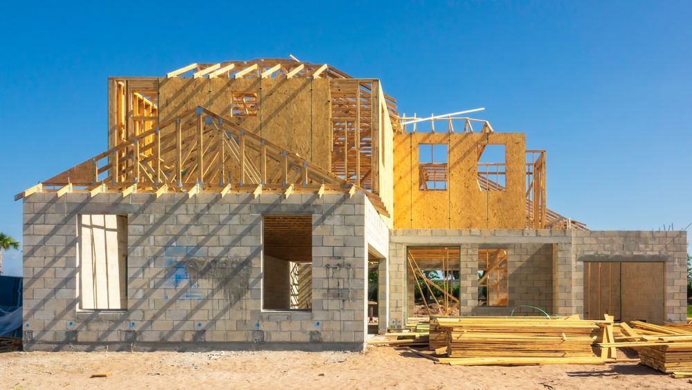 New home under construction with exposed wood framing and cinder block walls against a clear blue sky