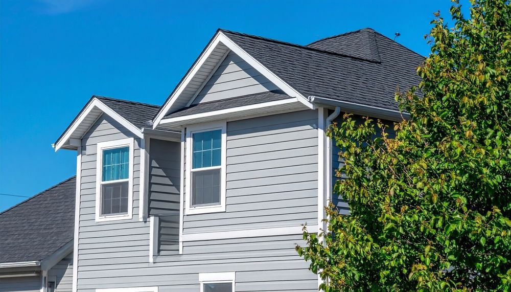 Gray house with white trim and dark roof against a clear blue sky