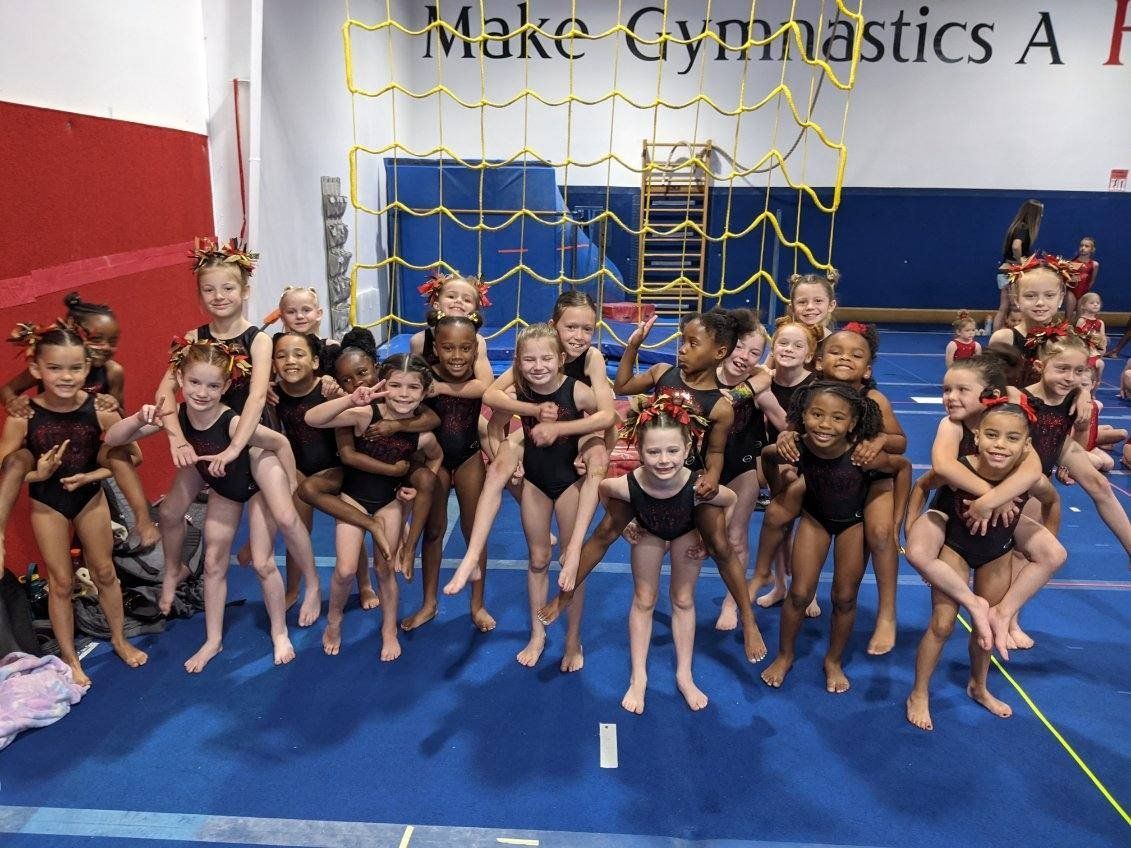 A group of young girls from the gymnastics team are posing for a picture