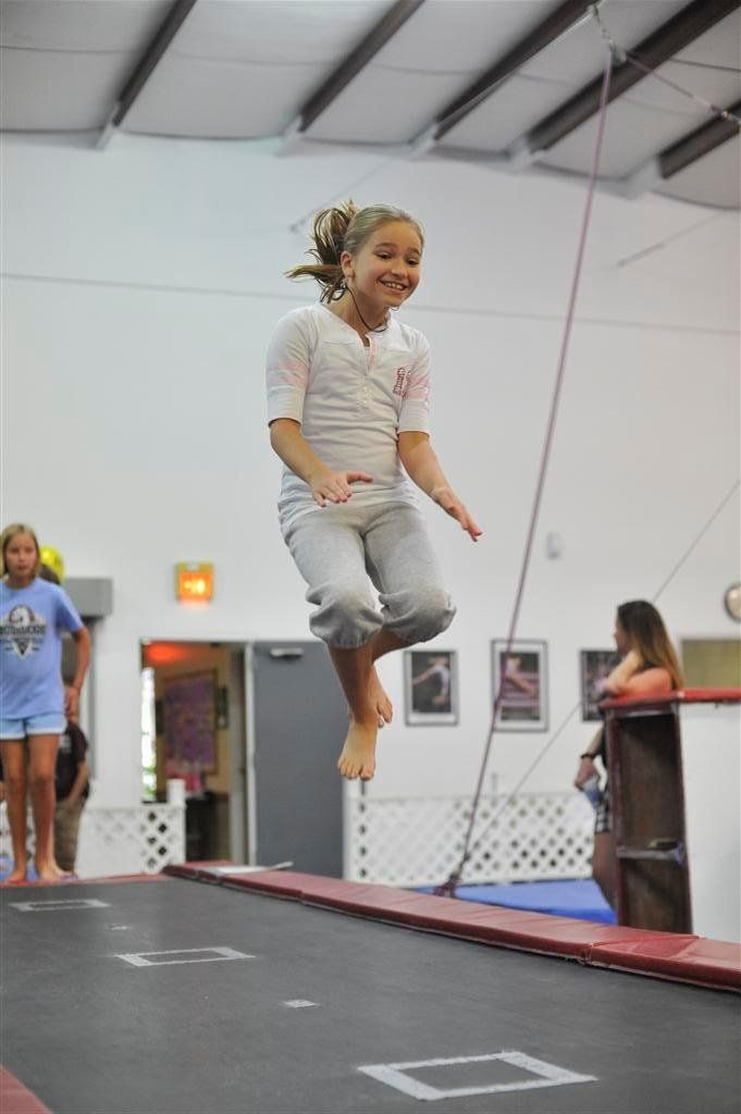 A young girl is jumping on a trampoline in a gym