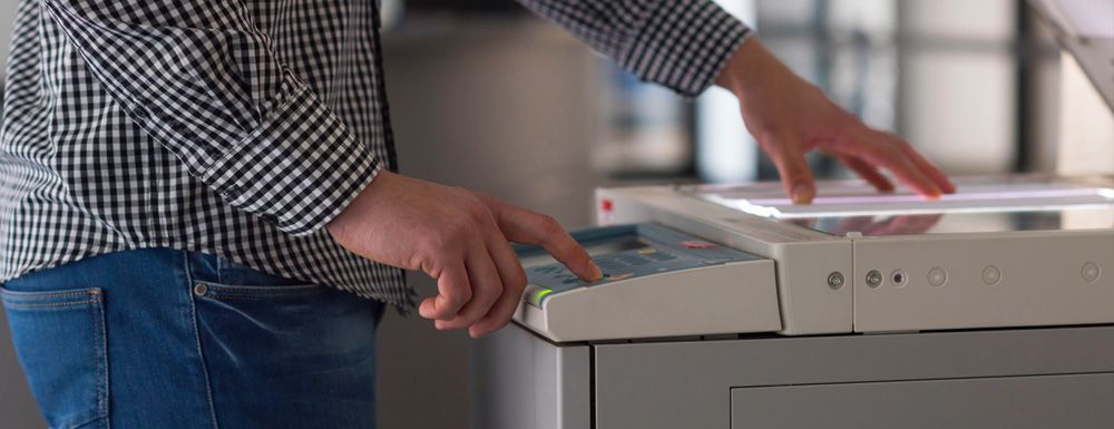 Person loading papers into a desktop copier or scanner office machine