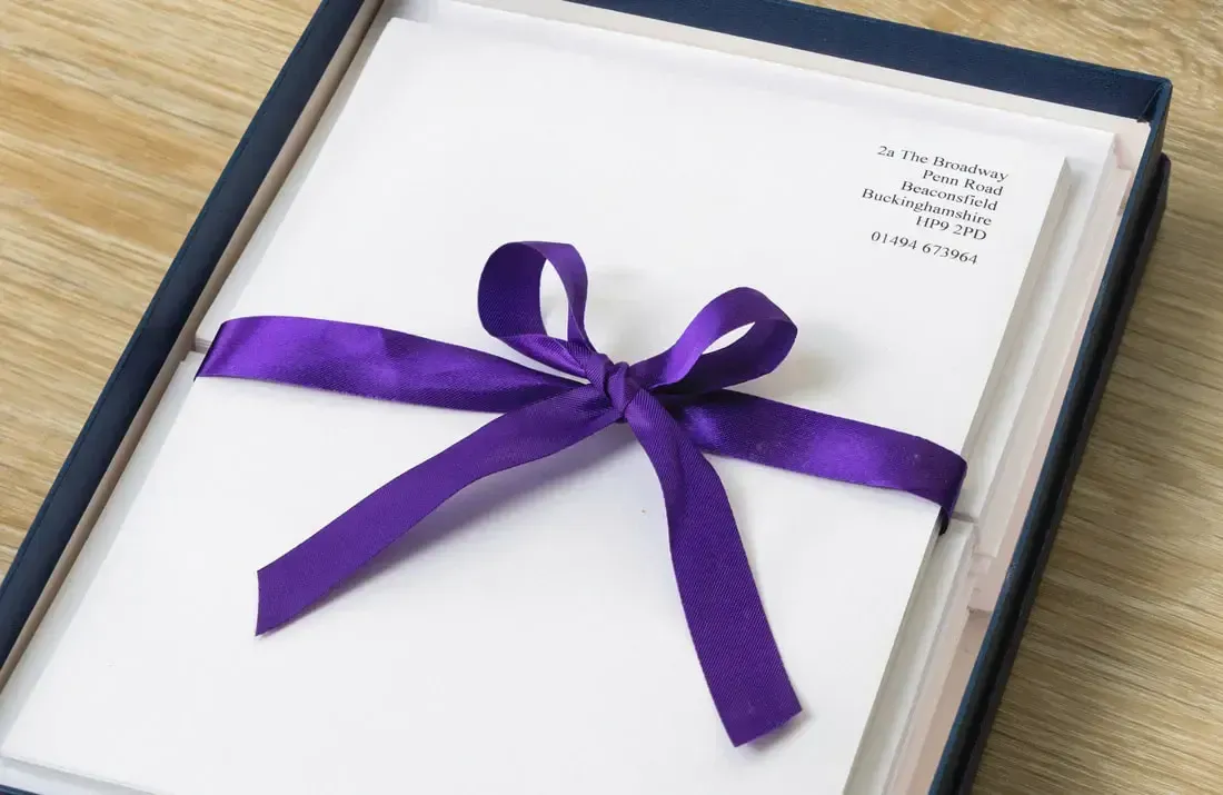 Purple ribbon tied around a white document in a blue gift box