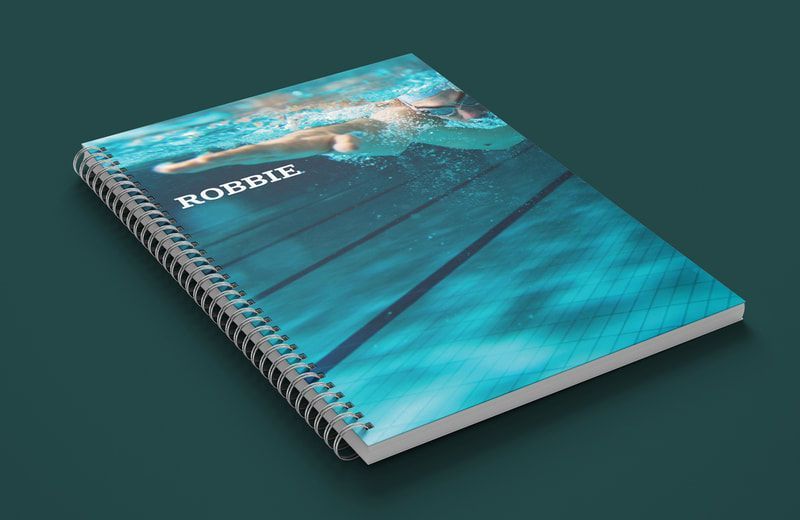 Spiral-bound notebook with turquoise cover and ocean-themed artwork on a dark background