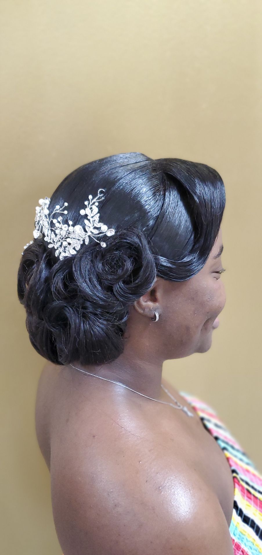 Side profile of a woman with an elegant updo and white floral hair accessory, wearing a striped top.