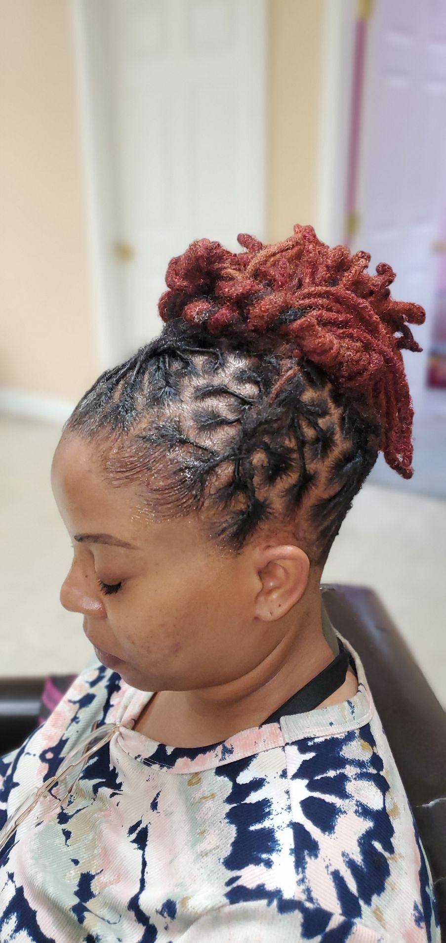 Profile view of a woman with red braided bun, looking down indoors