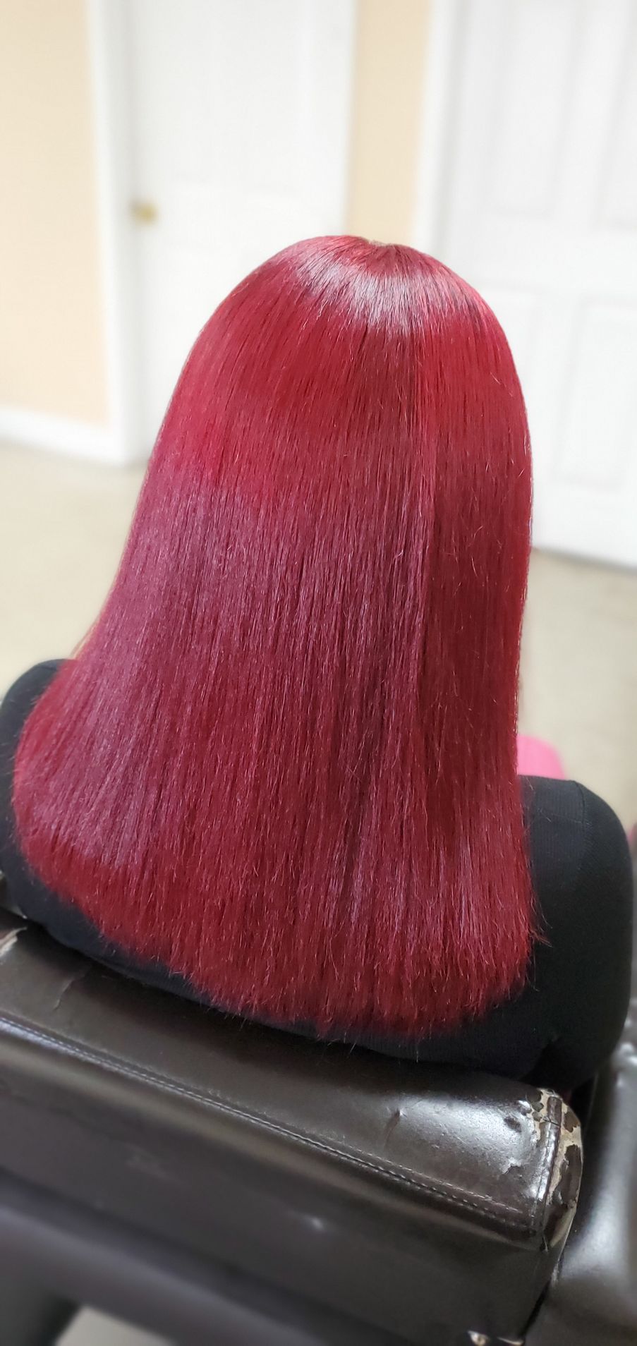 Red braided hairstyle viewed from the back on a black chair indoors