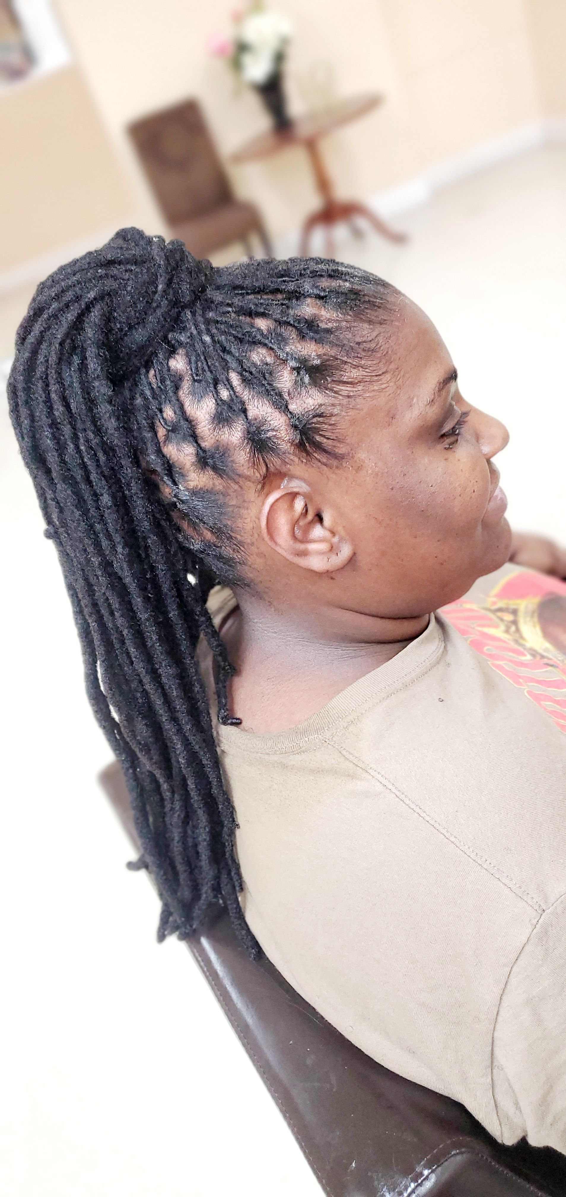 Side profile of a person with long braided hair sitting indoors on a chair