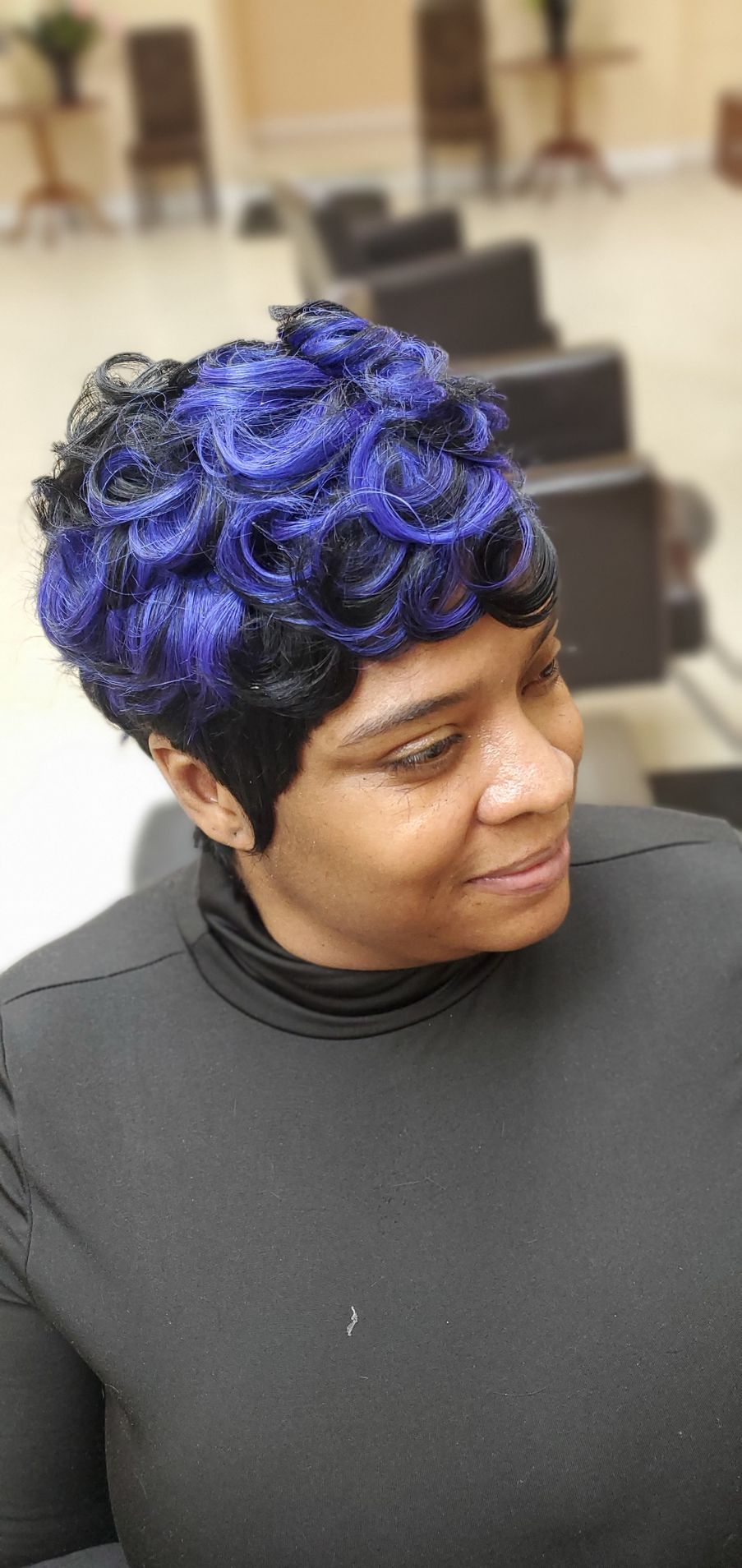 Person with blue curly hair looking down in a classroom setting