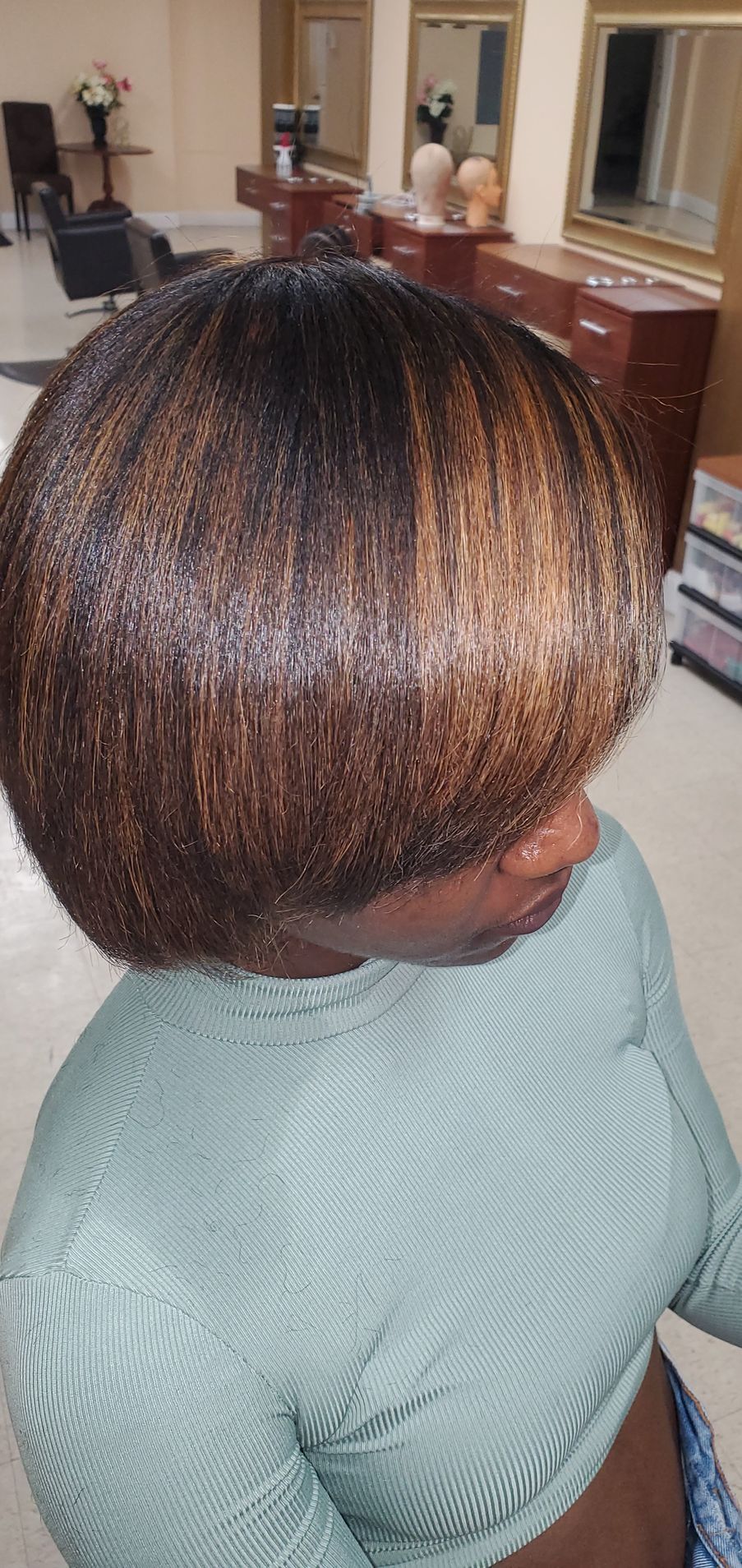 Side view of a short, layered brown bob hairstyle with auburn highlights in a home setting