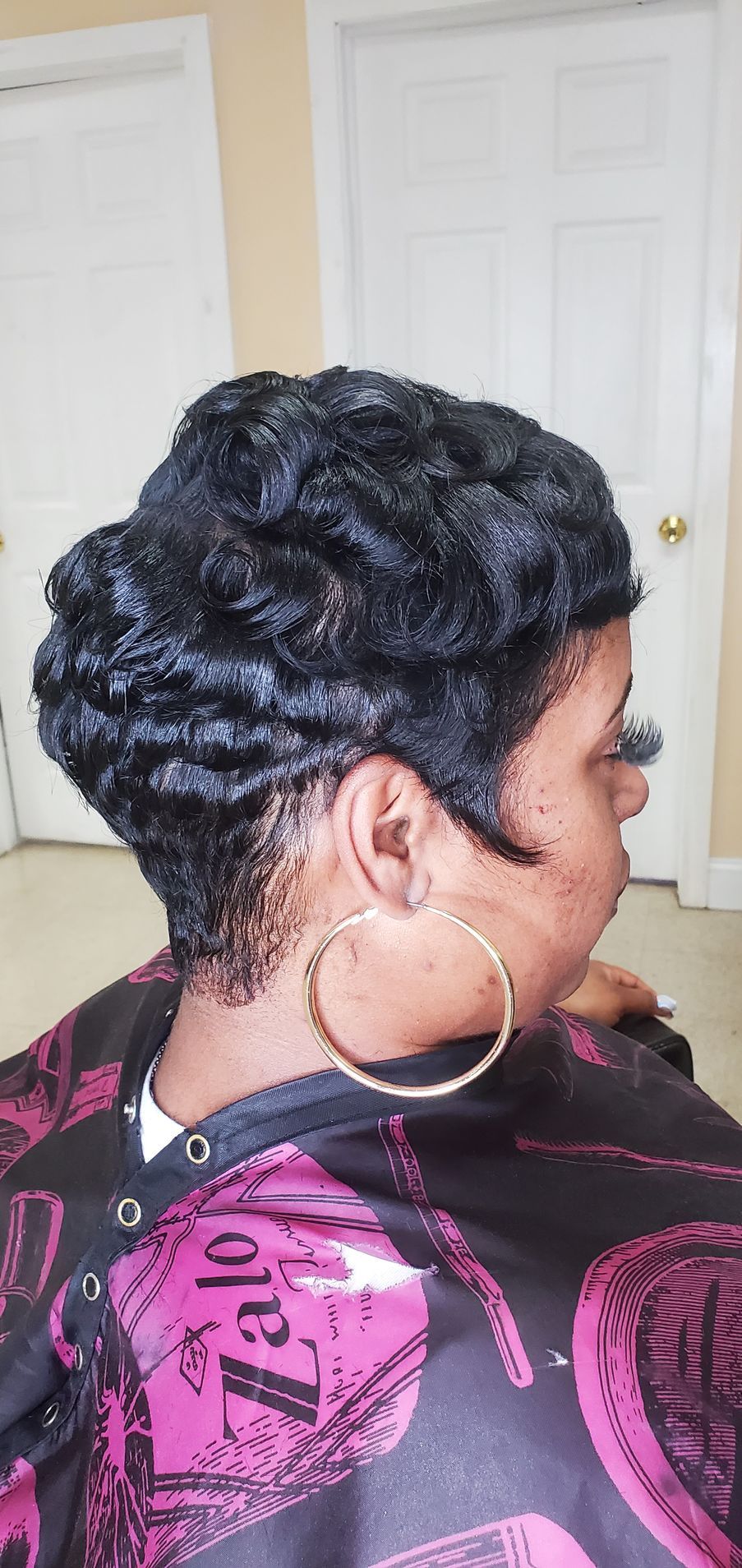Side view of an elegant braided updo with a large gold hoop earring and pink patterned top