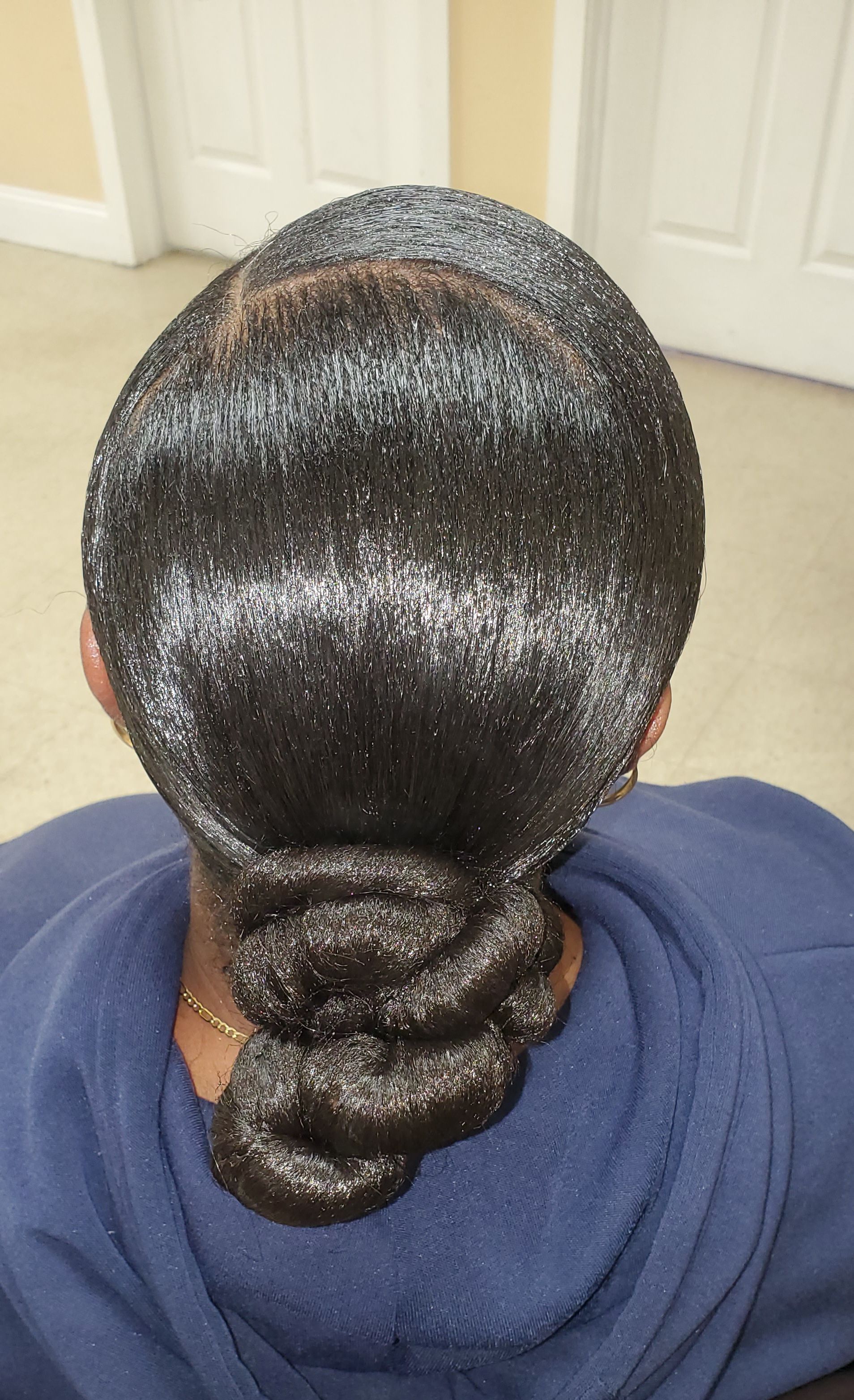 Back view of glossy black hair styled into a low braided bun