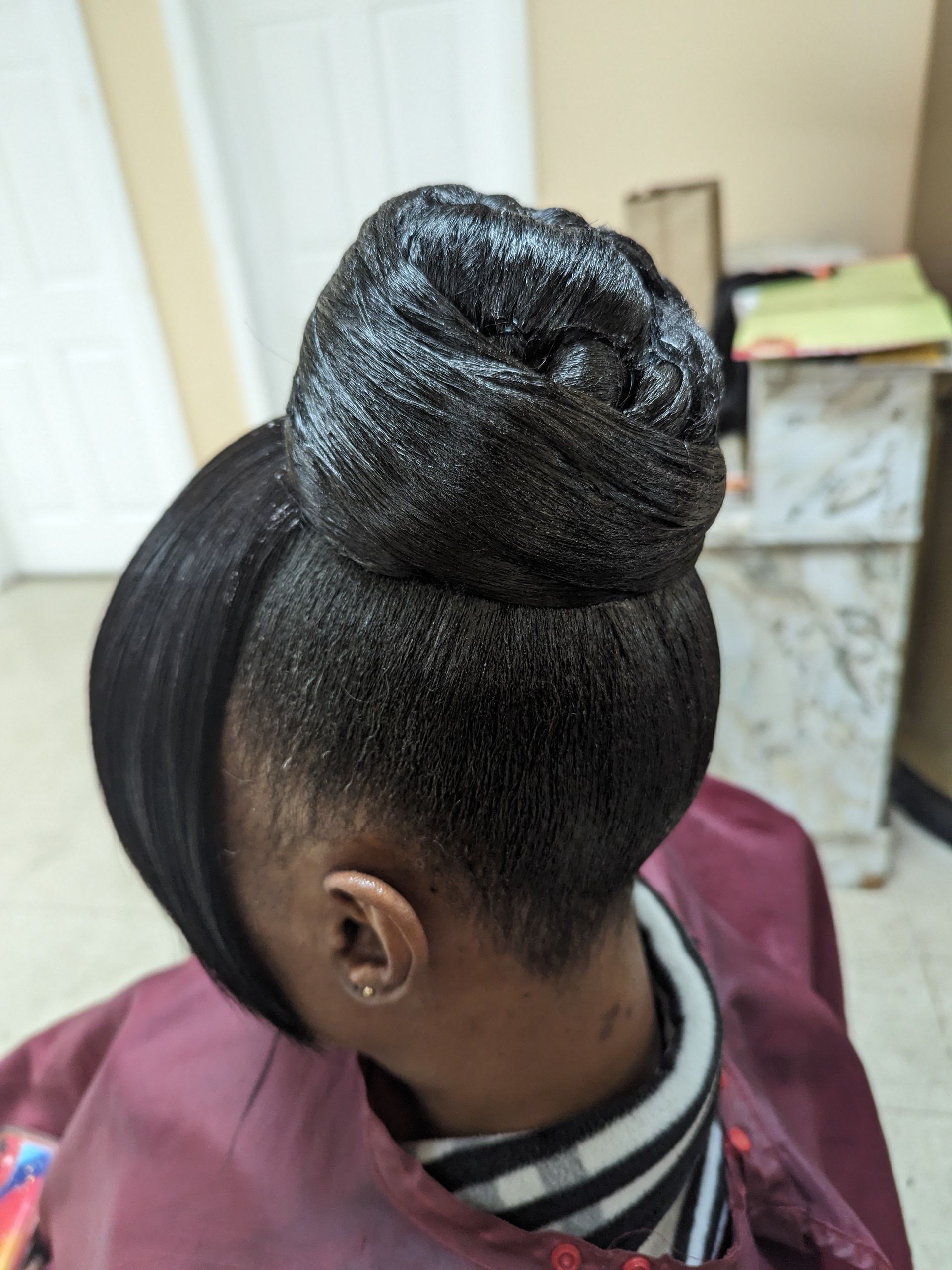 Close-up of an elegant braided updo with smooth side hair, indoors.