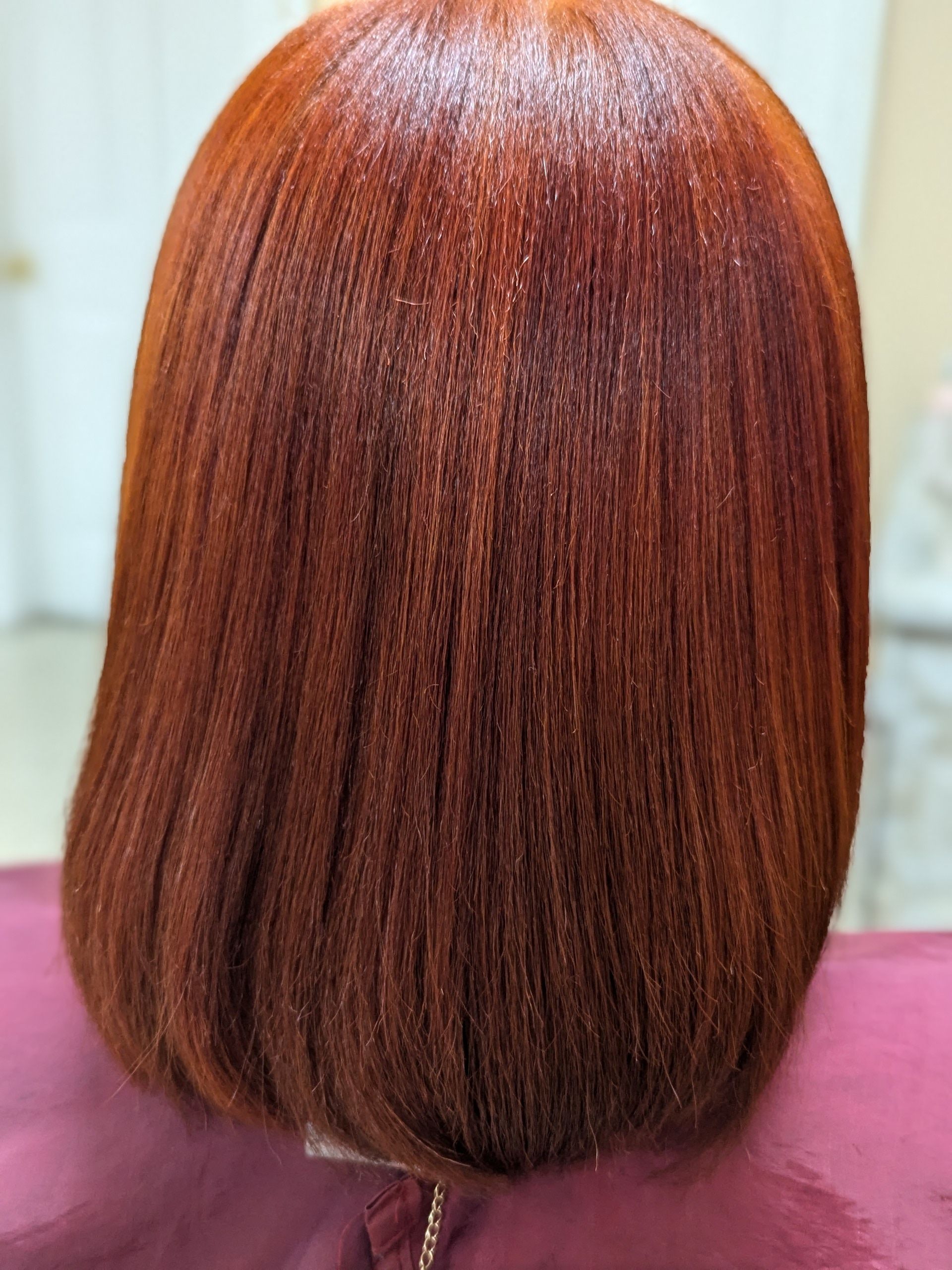 Short auburn bob hairstyle with a blunt cut, shown from the back on a mannequin head