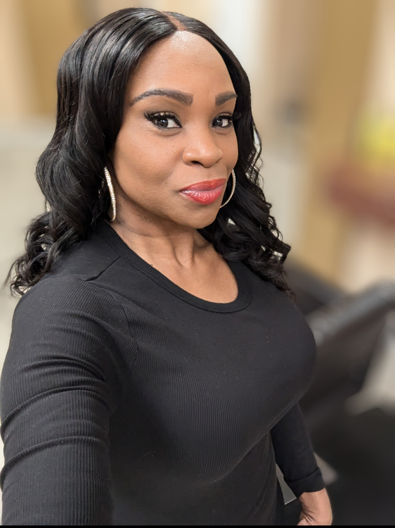 Woman in a black top taking a selfie indoors, with a softly blurred background