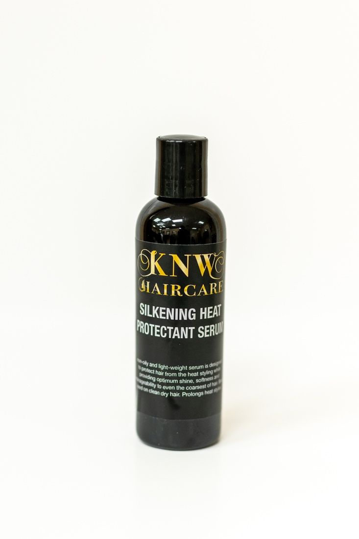 Black bottle of haircare product with gold label on a white background