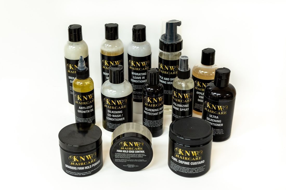 Assorted black, white, and gold KNV hair care bottles and jars arranged on a white background