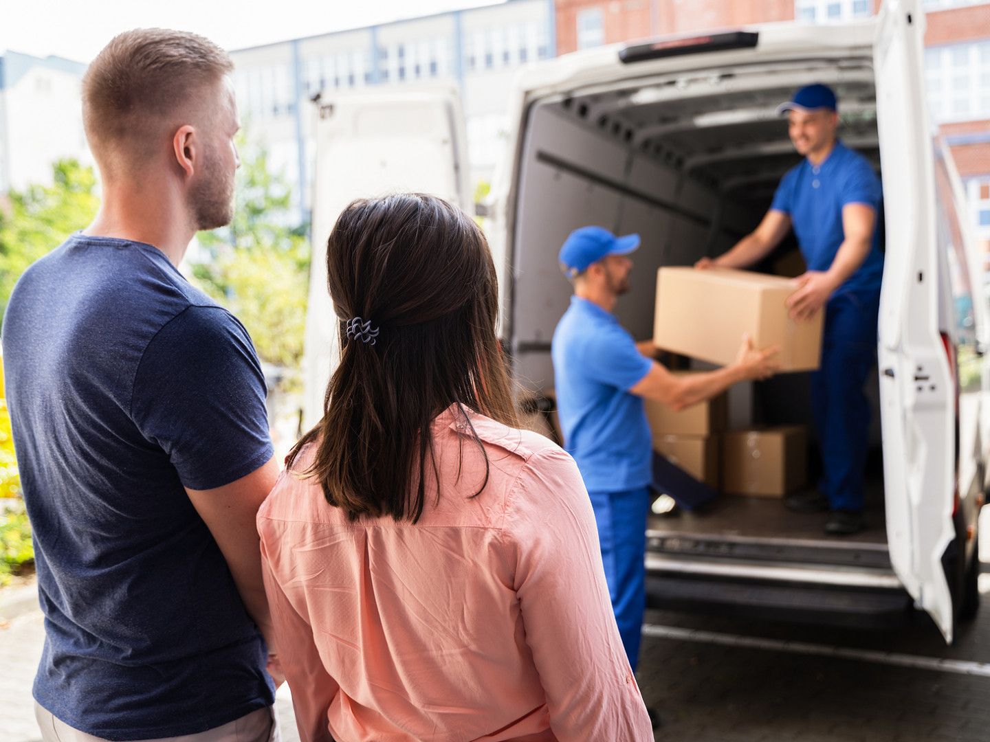 couple watching movers unload boxes from truck