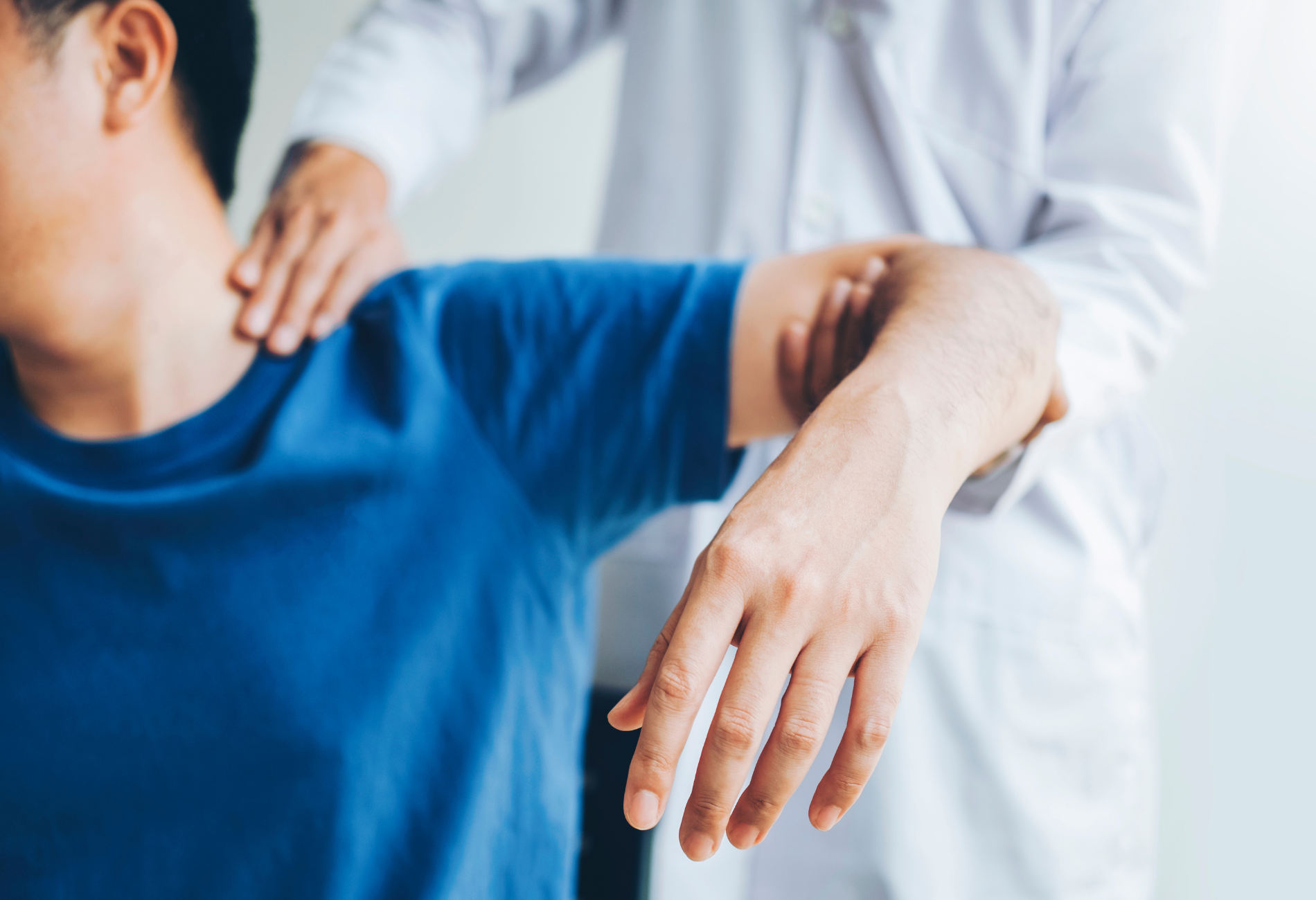 A doctor is examining a patient 's shoulder and arm.