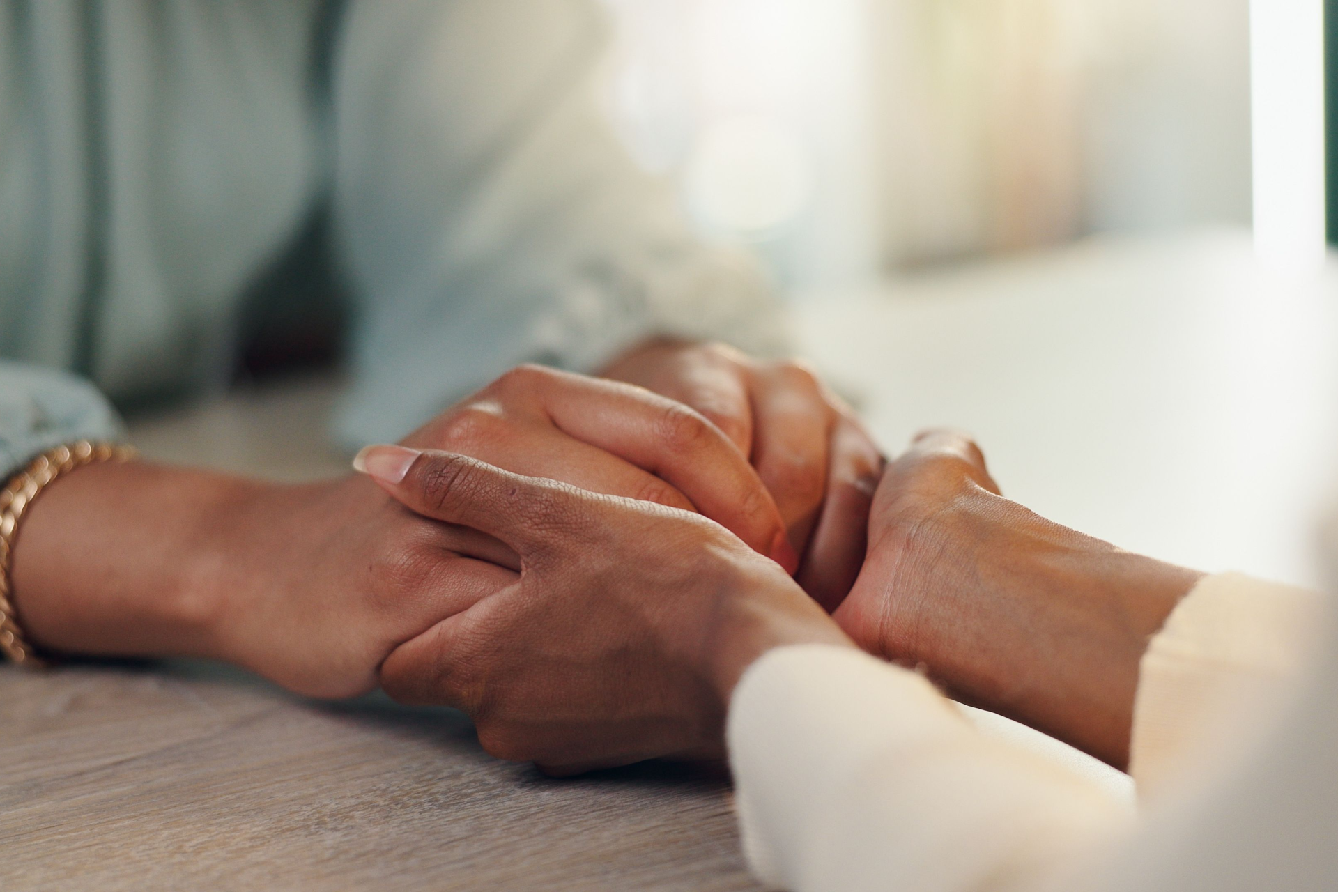 Hands gently clasped together in a comforting gesture across a table