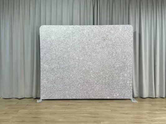 A white backdrop is sitting on a wooden floor in front of a white curtain.