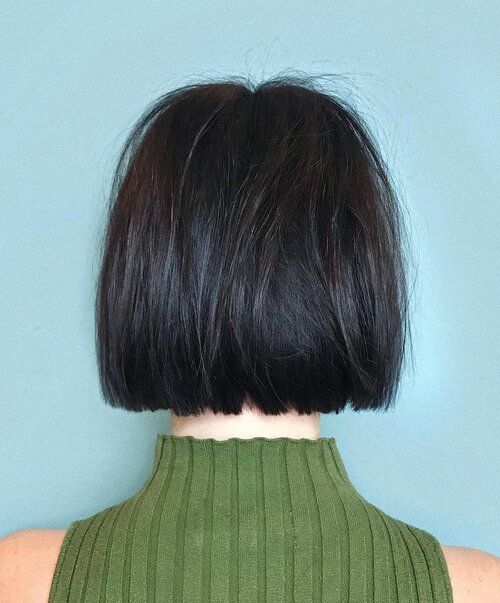 Back view of a person with a black bob haircut, wearing a green turtleneck.