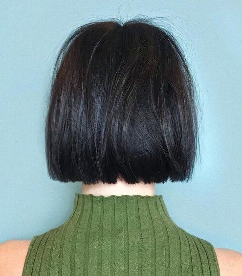 Back view of person with short, dark, straight bob haircut, wearing a green ribbed turtleneck.