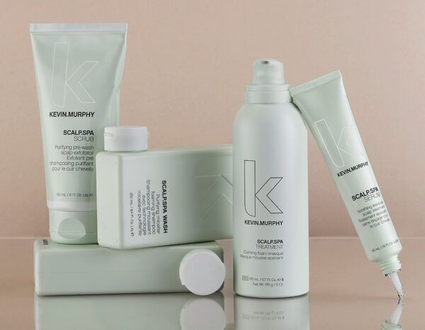 Five light green Kevin Murphy hair products on a neutral background.